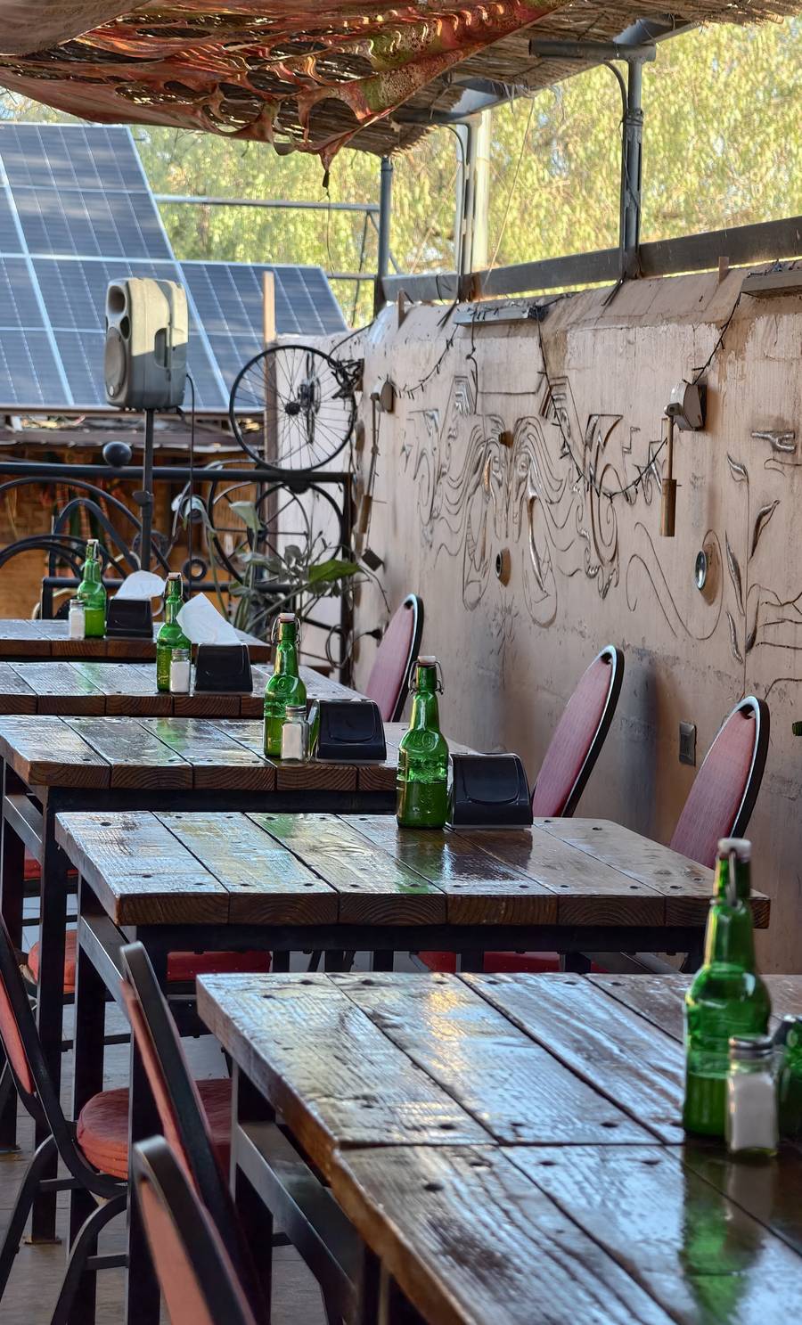 Terraza de día con mesas y mural en relieve